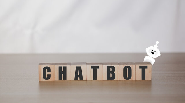 Business and technology concept. Wooden block with text and white robot. Chat bot with artificial intelligenc or Ai, Smart assitance communication.