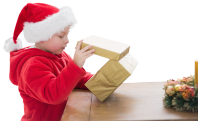Digital png photo of happy biracial boy in santa clothes opening gift on transparent background