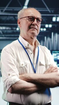 Vertical video Portrait of elderly engineer looking around modern server room in data center, preparing to start comission on malfunctioning high tech facility hardware rigs in order to ensure