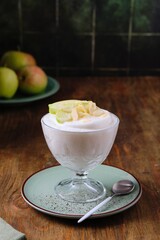 Dessert, airy apple mousse garnished with almond and apple slices, in a transparent bowl on a brown...