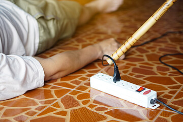 Using wooden stick is moving away the electric plug socket from the unconscious man who lay down on...