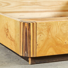 Luxurious olive ash burled wood platform bed frame. Vintage 1980s light wood furniture. Close-up of...