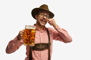 Portrait of attractive young man in hat, wearing folk Bavarian clothes, holding beer mug isolated white background. Concept of Oktoberfest - obrazy, fototapety, plakaty