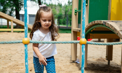 The child plays in the outdoor playground. Children play in the courtyard of a school or kindergarten. Healthy summer fun for kids.