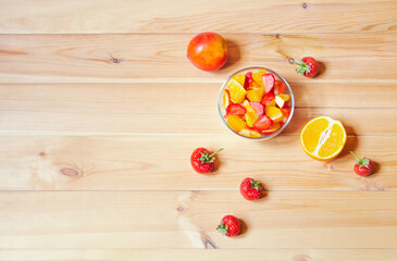 Fruit salad and fresh fruits on wooden table. Top view, copy space.