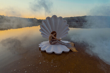 Beautiful redhead woman as mermaid with giant seashell