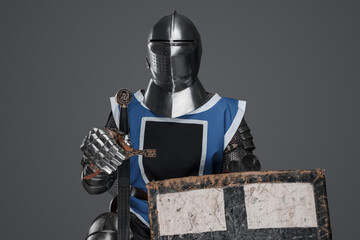 Blue surcoat-wearing medieval knight with sword and shield on gray background