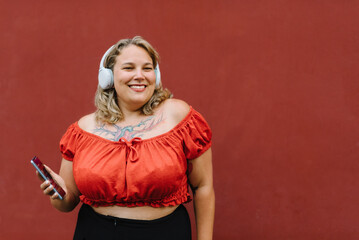 Cheerful plump woman with smartphone listening to music