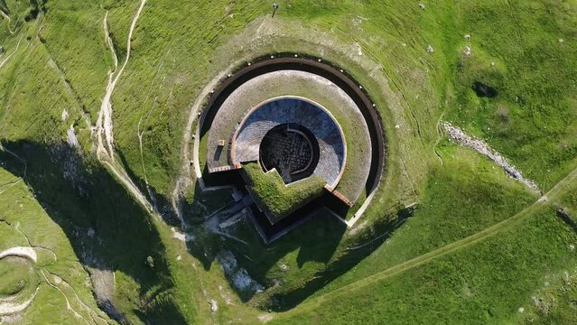 Aerial drone view of round fort called Fort de Ronce, Val Cenis, Savoie, Rhone Alpes, France. Bird eye panoramic view of old military fortification in French Alps, overgrown with bright green grass