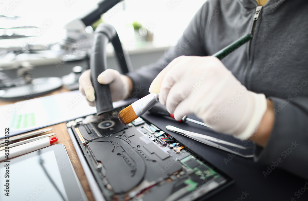 Wall mural male chemist in white protective gloves use vacuum cleaner in laptop repair service. technical preve