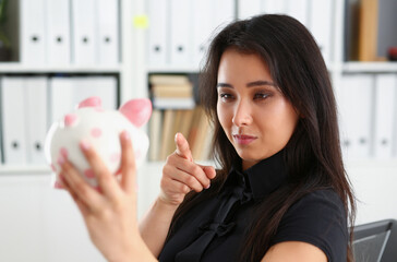 young beautiful brunette woman hold piggybank in arms