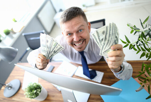 Handsome smiling adult caucasian businessman hold dollar paper cash bancnote in hands against office background. Fast business startup education concept. Financial bill economy project