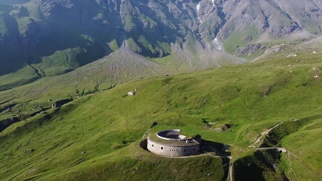 Aerial drone view of round fort called Fort de Ronce, Val Cenis, Savoie, Rhone Alpes, France. Bird eye panoramic view of old military fortification in French Alps, overgrown with bright green grass