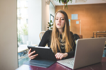 Fototapeta premium Young businesswoman young multitasking using computer and tablet