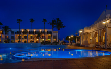 Fototapeta na wymiar illuminated swimming pool in the courtyard of a mediterranean hotel at dusk