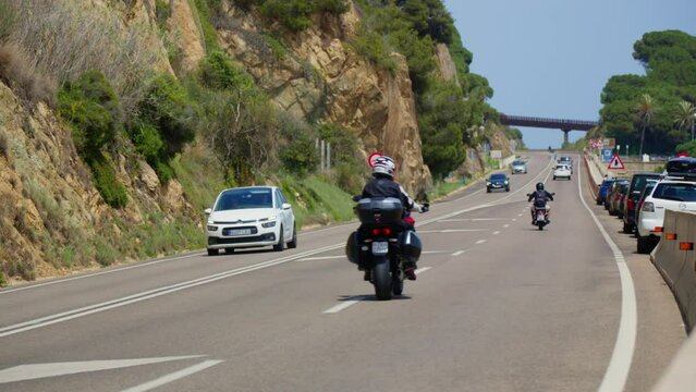 A motorcyclist and a car are driving along the road