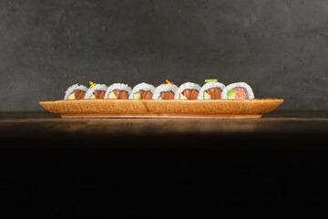 Row of fresh California sushi rolls with salmon served on wooden tray