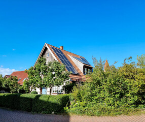house and garden with bushes and trees at the countryside, solar panels on the roof of the house 