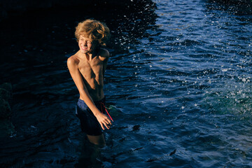 Fototapeta premium Boy grimacing in wavy sea with splashing water