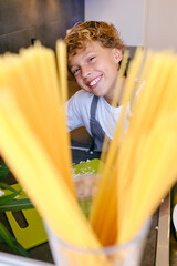 Cheerful boy cooking in kitchen at home