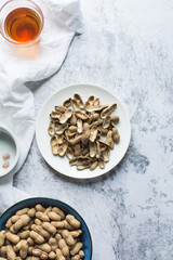 Top view of groundnut shells in a white plate, flatlay of shelled peanut in a white plate on a marble countertop, nigerian roasted groundnut shells in a bowl