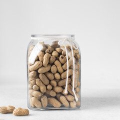 shelled groundnut in a glass jar, peanuts in shell in a transparent jar on a marble countertop, nigerian roasted groundnut in a glass container