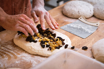Detail of a baker's hands introducing ingredients into the bread
