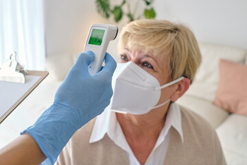 Crop physician measuring temperature of patient with infrared th