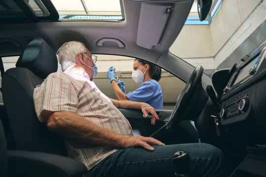 Crop nurse filling syringe with vaccine against driver in car