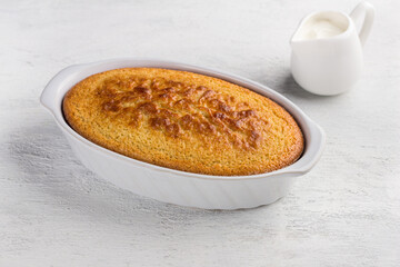 Freshly prepared mannik, semolina pie in the form with sour cream on light gray background