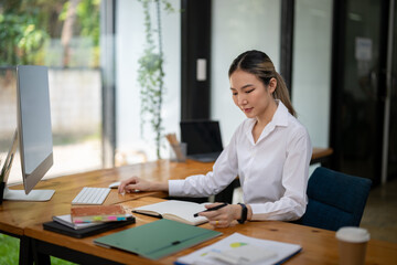 Asian businesswoman thinking about a new project and taking note of new ideas.