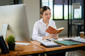 Businesswoman checking the neatness of the project plan from notes in a notebook