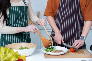 Happy portrait of loving young asian of having fun standing a cheerful preparing food and enjoy cook cooking with vegetables, meat, bread while standing on a kitchen Condo life or home