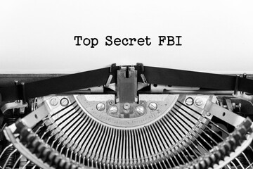Top secret FBI phrase closeup being typing and centered on a sheet of paper on old vintage typewriter mechanical