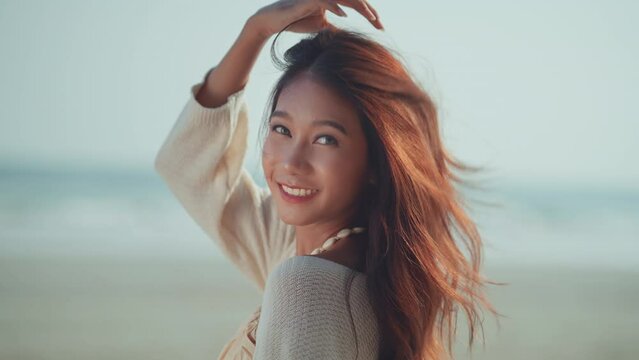 Happy smiling young asian woman on tropical beach, Carefree female smiling and enjoying breeze with sea in background. Travel vacation, summer outdoor pleasure.