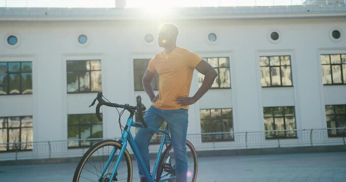 Sunbeams illuminate African American guy sitting on bicycle