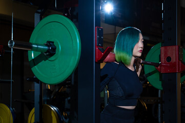 pretty fashion hairstyle asian woman practice routine weightlifting with barbell rack at modern gym, active fitness people workout weight training strength body and mental health in dark sport club