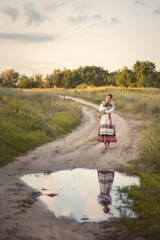 Photo of a girl in a folk costume on a country road.