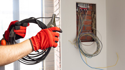 Hands electrician with wire. Electrification house under construction. Electrician cuts wire....