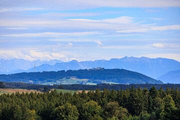 Alpine view over meadows and field paths towards the Alps near Reichling in Bavaria on a summer day with blue sky and light clouds