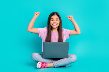 Full body photo cadre of small cute schoolgirl fists up enjoy playing computer games online victory isolated on cyan color background