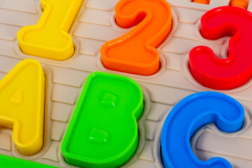 Close up photo of kids toy multi colored numbers and alphabet letters.