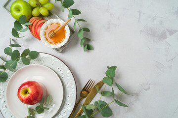 Jewish holiday Rosh Hashana festive table setting with plate, honey, apple and eucalyptus leaves on bright background. Top view, flat lay