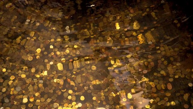 Treasures at the bottom of the ocean. Gold coins underwater. Lots of coins in the fountain. Waves and swaying movement of water. Coin money.