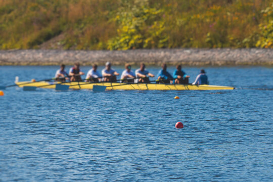Group of rowing team athletes sculling during competition, kayak boats race in a rowing canal, regatta in a summer sunny day, canoeing water sports team training in a river