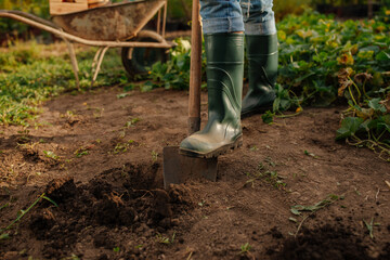 Shot of garden boots and shovel hoeing the ground in the garden