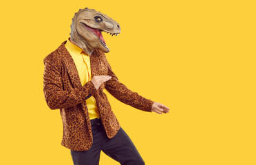 Funny reptile dancing on yellow studio background. Side view of happy man in leopard jacket and...