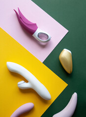 Collection of different types of sex toys on a pink, green and yellow background. - 633455947