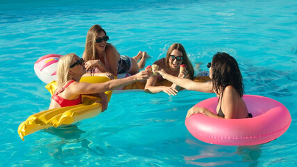 A group of beautiful, young women are eating strawberry popsicles and having fun in the pool.