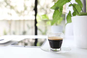 Coffee glass cup and tablet and plant pot on white desk